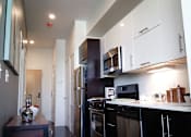 Thumbnail 26 of 36 - Modern galley kitchen with white and dark cabinetry at 68 Beale Apartments, Quincy